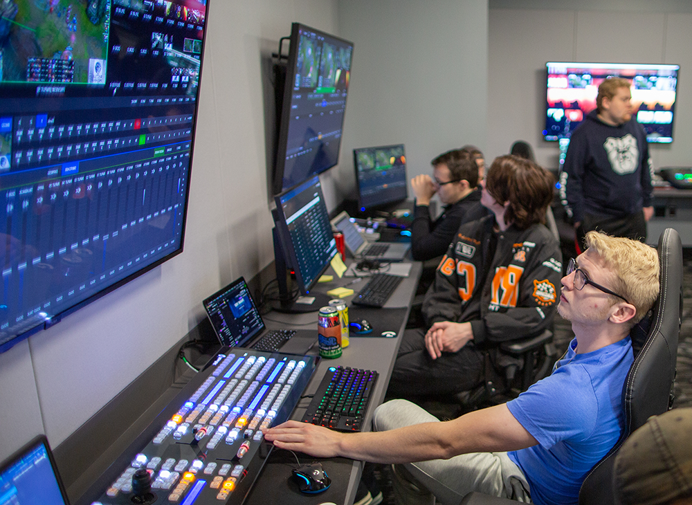 电子竞技工作室的一群男性，拥有大型游戏屏幕和媒体控制板